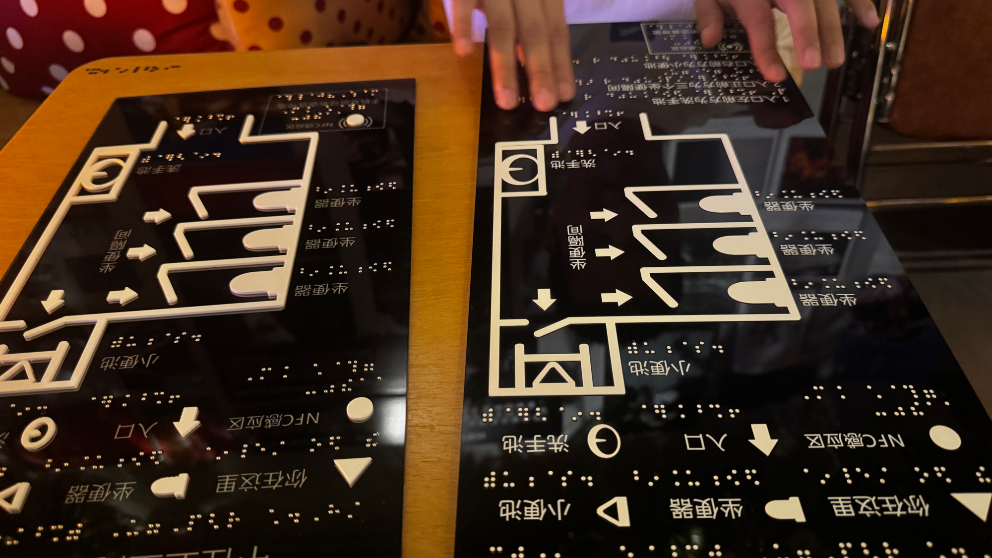 A/B 两版实体触摸地图原型：黑色亚克力面板上以凸起白色图形标识入口、你在这里、洗手池、坐便隔间、小便池与 NFC 感应区，并带有盲文标签
